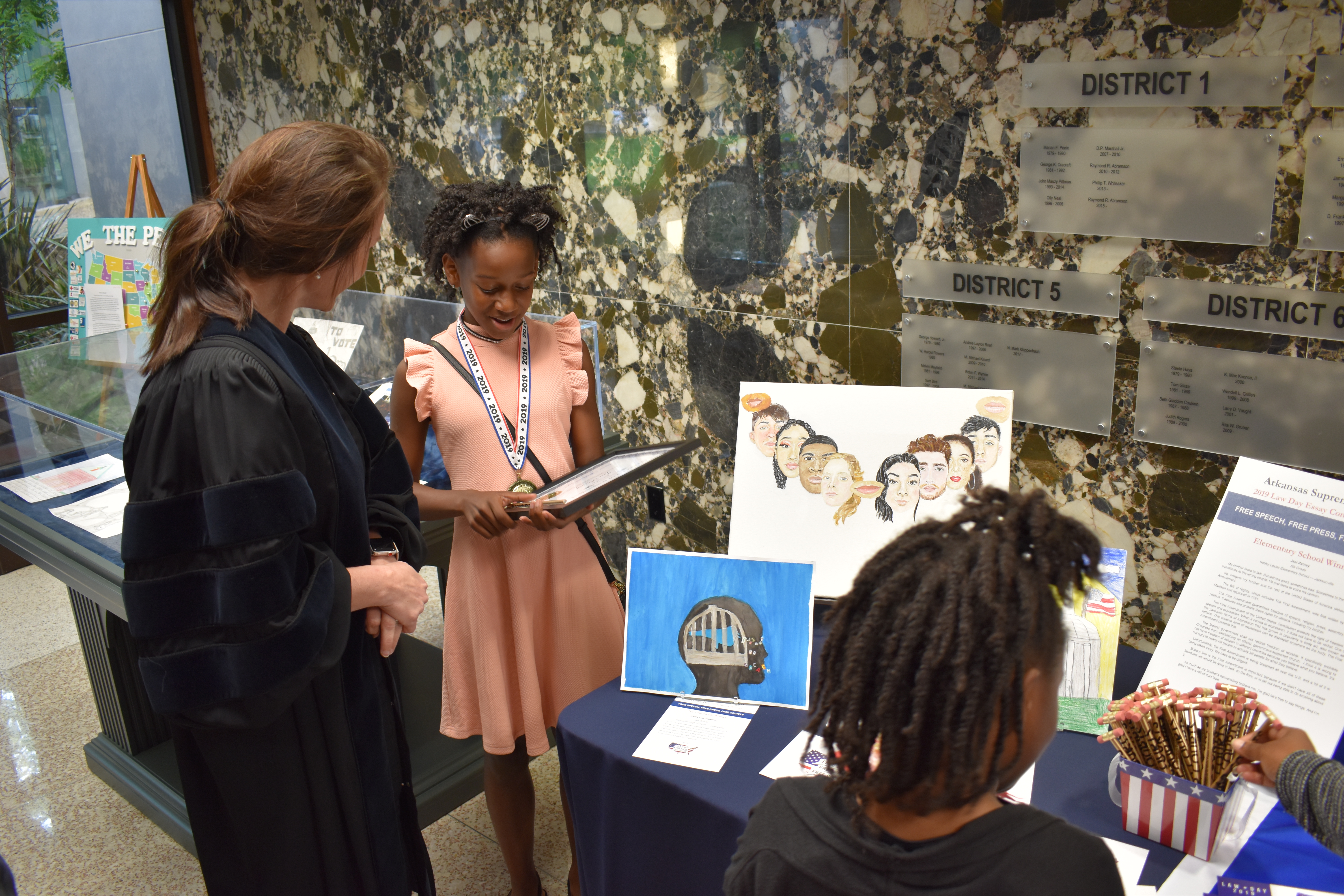 Justice Wood viewing law day art with two children during a tour
